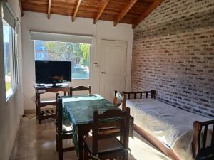 a room with a table and a tv and a brick wall at Cabaña Alberto in Balneario Claromecó