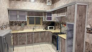 a kitchen with wooden cabinets and a stove top oven at Zahraa Al-Tal in Baljurashi