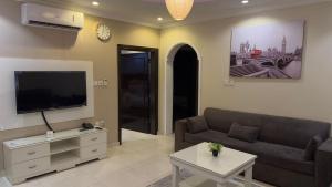 a living room with a couch and a flat screen tv at Zahraa Al-Tal in Baljurashi