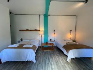two beds in a room with two lamps at La Tozi Hotel in San Cristóbal de Las Casas