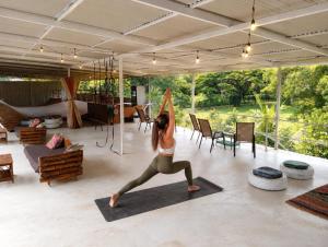 a woman doing a yoga pose in a living room at Cool Vibes Beach Hostel in Dominical