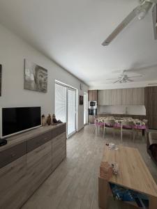 a living room with a television and a dining room at Apartman Aloe in Mali Lošinj