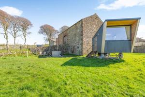 a tiny house on a grass field next to a stone building at 1 Bed in Ponsonby oc-l37879 in Gosforth