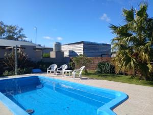a swimming pool with two chairs and a table next to it at Cabaña Alberto in Balneario Claromecó