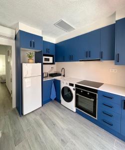 a blue kitchen with white appliances and blue cabinets at Apartamento Galvana in Peniscola