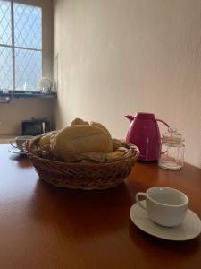 a basket of bread sitting on a table with a cup at Loft Campinho 1 in Estação Inhoaíba