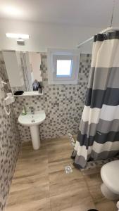 a bathroom with a sink and a shower curtain at Anemos Comfort Living in Paralia Panteleimonos +40 photos