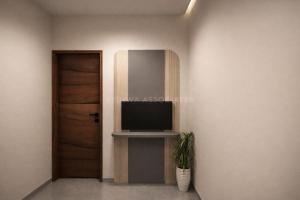 a room with a television and a door and a plant at विठाई AC Rooms in Pandharpur
