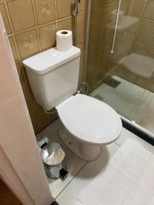 a white toilet in a bathroom with a shower at Loft Campinho 1 in Estação Inhoaíba +2 photos