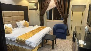 a hotel room with a bed and a blue chair at Zahraa Al-Tal in Baljurashi