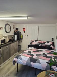a bedroom with a bed and a clock on the wall at Nett'Als Lodge Studio Apartment in Derby