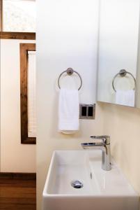a white bathroom with a sink and a mirror at NEW! Modern Cabin Tiny Home at Cliffside #1 in Orderville