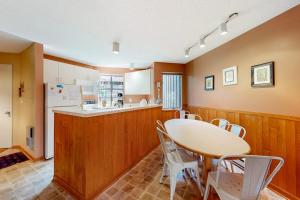 a kitchen with a table and white chairs and a counter at Hawks Nest 27 in Glen Arbor