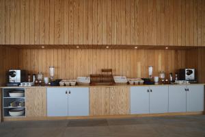 a kitchen with white cabinets and a wooden wall at Hotel Mezio National Park in Soajo