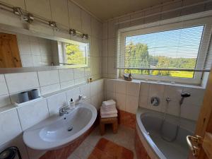 a bathroom with a sink and a tub and a window at Ferienhaus Hofgut von Schaewen in Waldesch +21 photos
