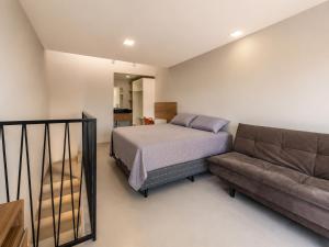 a bedroom with a bed and a couch at Pousada Soul Papagaio - lofts completos a 30 metros do mar in Palhoça