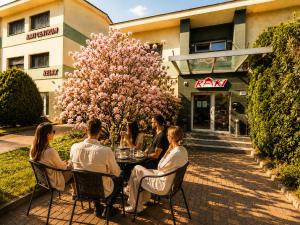 Eine Gruppe von Menschen sitzt an einem Tisch vor einem Gebäude in der Unterkunft Penzion RAKI in Bratislava