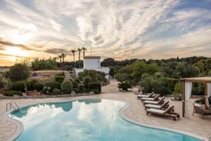 a swimming pool with lounge chairs and a resort at Masseria Tenuta Specolizzi in Lido Marini