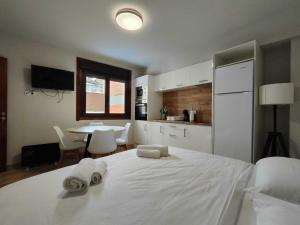a bedroom with a large white bed with towels on it at Habitación con cocina en Muralla Lugo 1.3 C in Lugo