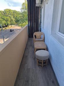 a balcony with two chairs and a stool and a window at Centralhome in Miskolc