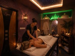 a woman getting a massage from a woman laying on a bed at Hotel Vents Des Iles in Essaouira