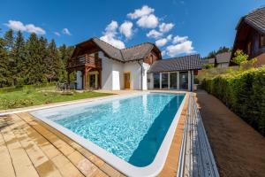 a swimming pool in front of a house at Villa Gamma - Lipno Home in Lipno nad Vltavou