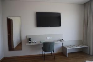 a room with a chair and a television on a wall at Hotel Mezio National Park in Soajo