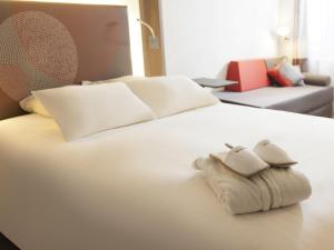 a white bed with two towels on top of it at Novotel Nottingham Derby in Long Eaton