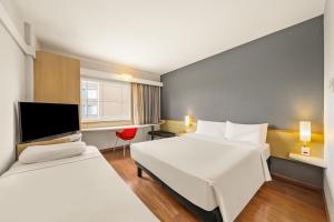 a hotel room with two beds and a tv at Slim Hotel Campinas in Campinas