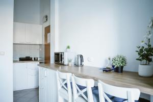 a kitchen with white cabinets and a counter with white chairs at Apartmants Bubalo in Trpanj +16 photos