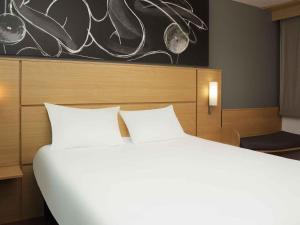 a bedroom with a large white bed and a painting at ibis 3 Lacs Neuchâtel in Thielle