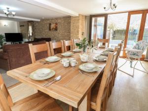 a wooden dining room table with plates and utensils at Tithe Barn, Lyneham in Bruern