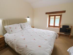 a bedroom with a white bed with flowers on it at Tithe Barn, Lyneham in Bruern