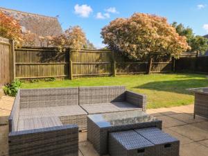 a patio with a couch and tables in a yard at Tithe Barn, Lyneham in Bruern