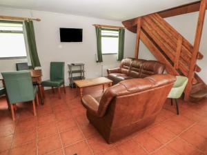 a living room with a leather couch and chairs at Cabin No 13 - Salt and Fern Cabins in Port Talbot