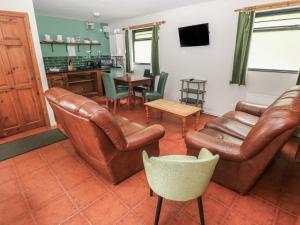 a living room with leather furniture and a kitchen at Cabin No 13 - Salt and Fern Cabins in Port Talbot