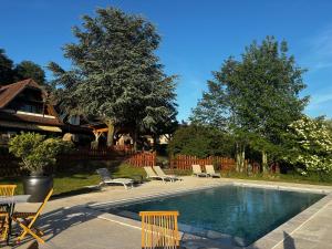 a swimming pool with chairs and a house at Relais Équestre du Neufeld - Roulotte Nature in Oberhaslach