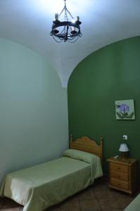 Habitación verde con cama y lámpara de araña. en Casa Rural Pastora Marcela, en Saceruela