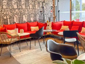 a red couch in a room with tables and chairs at ibis Nîmes Ouest - A9 in Nîmes