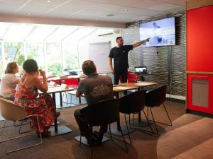 a man standing in front of a presentation in a classroom at ibis Chalon Sur Saone Nord in Chalon-sur-Saône
