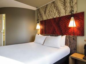 a bedroom with a white bed with two pillows at Ibis Schiphol Amsterdam Airport in Badhoevedorp +140 photos