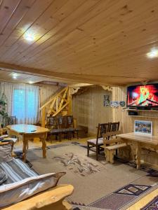 a living room with wooden ceilings and tables and a tv at KarpatskeDzerelo in Roztoky