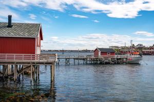a dock with a red house and a boat on the water at Reine seaview cabin in Reine