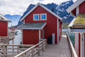 a red house on a dock with mountains in the background at Reine seaview cabin in Reine