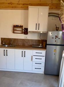 a kitchen with white cabinets and a refrigerator at Charming Village Farmhouse, Çukë in Sarandë