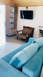 a living room with a blue couch and a tv at Charming Village Farmhouse, Çukë in Sarandë