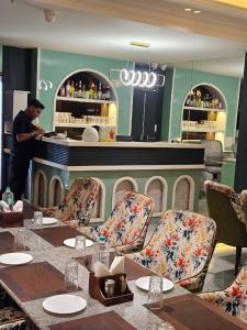 a man standing at the counter of a restaurant with tables and chairs at Hotelyashraj in Pipra Dewās