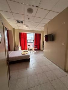 a bedroom with a bed and a table and a room with red curtains at Hotel Las Peñas in Guayaquil