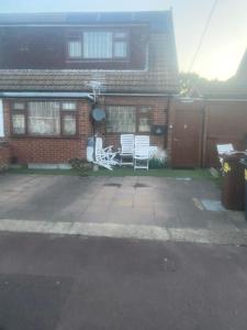 a house with two white chairs in the yard at A Spacious Odyssey in Dagenham