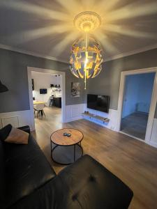 a living room with a couch and a chandelier at patriciervilla i 2plan udlejes in Hjørring +14 photos